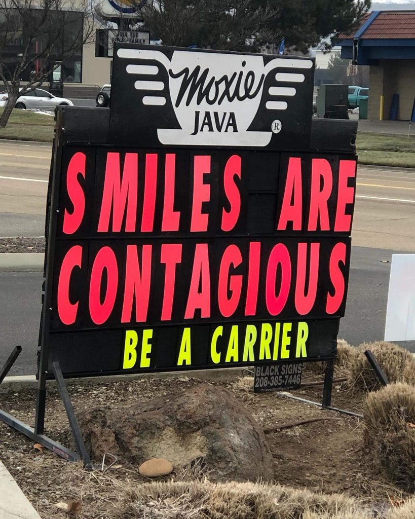 Outdoor sign for Moxie Java coffee shop with words "Smiles are contagious be a carrier"